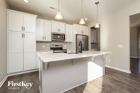 A kitchen with white cabinets and a white island.