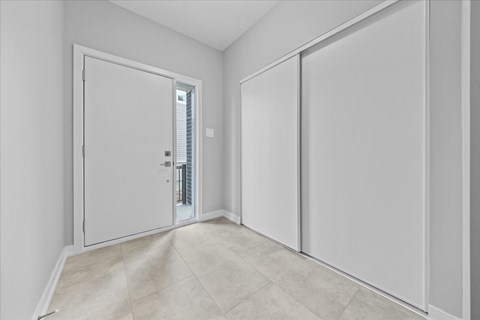 A white door is open to a hallway with a tiled floor.