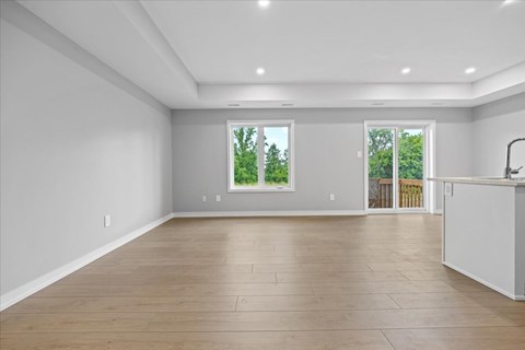 A spacious room with wooden flooring and two windows.