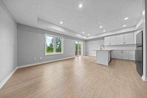 A spacious kitchen and living room with wooden flooring and white cabinetry.