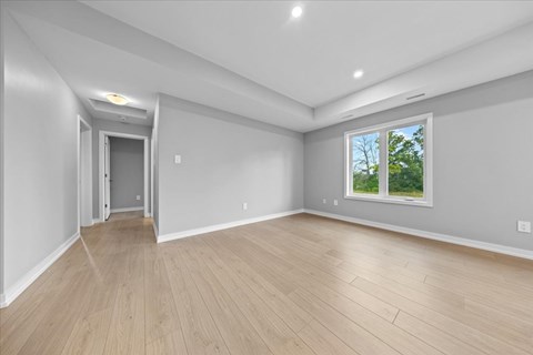 A room with a wooden floor and a window showing greenery outside.