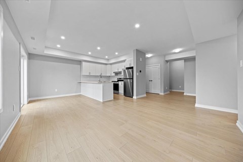 A spacious kitchen with wooden flooring and white walls.