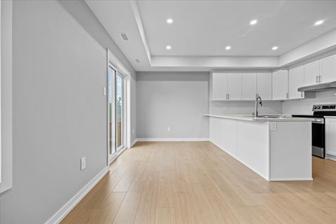 A kitchen with white cabinets and a wooden floor.