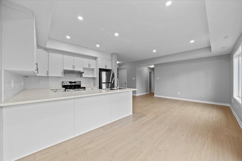 A modern kitchen with white cabinets and a wooden floor.
