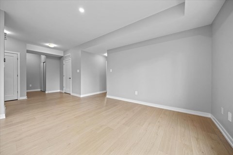 A spacious room with wooden flooring and white walls.