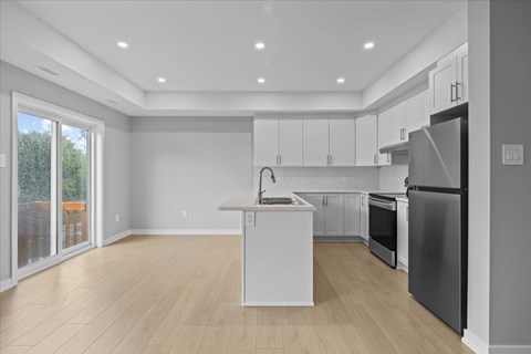 A kitchen with a refrigerator, oven, and cabinets.