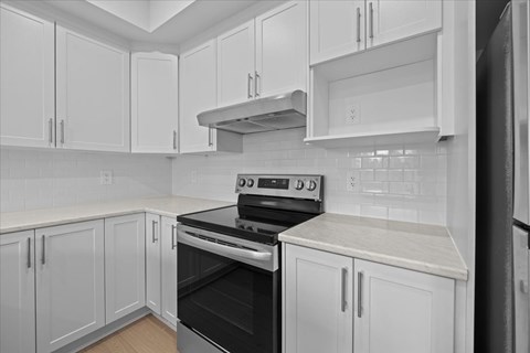 A kitchen with white cabinets and a black stove top oven.