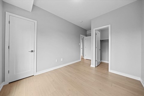 A room with white walls and wooden flooring with two doors.