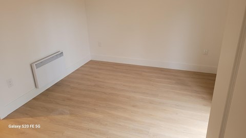 A room with a wooden floor and a radiator on the wall.