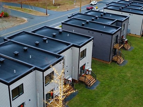 A series of houses with black roofs are lined up in a row.