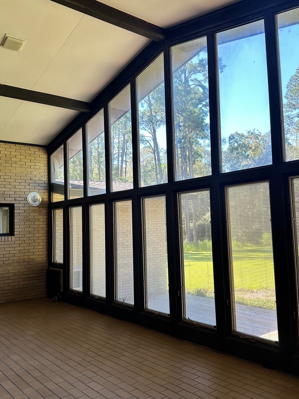 A room with a large window overlooking a green lawn.
