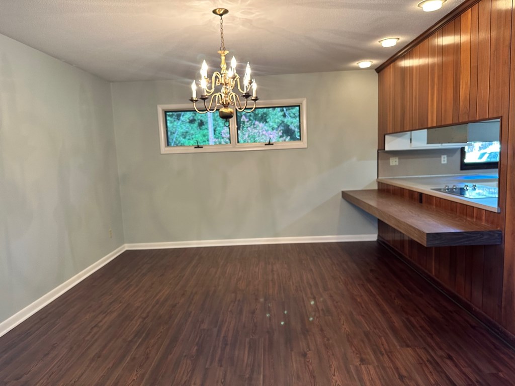 A room with a wooden floor and a chandelier hanging from the ceiling.