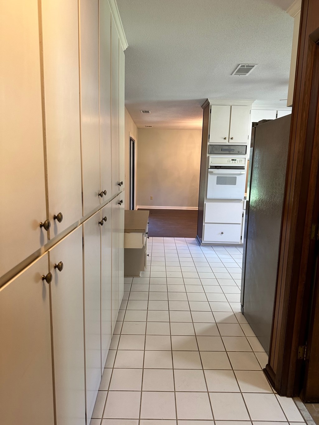A kitchen with white cabinets and a black fridge.