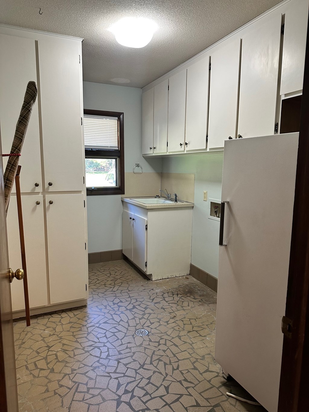 A kitchen with white cabinets and a white refrigerator.