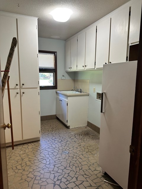 A kitchen with white cabinets and a white refrigerator.