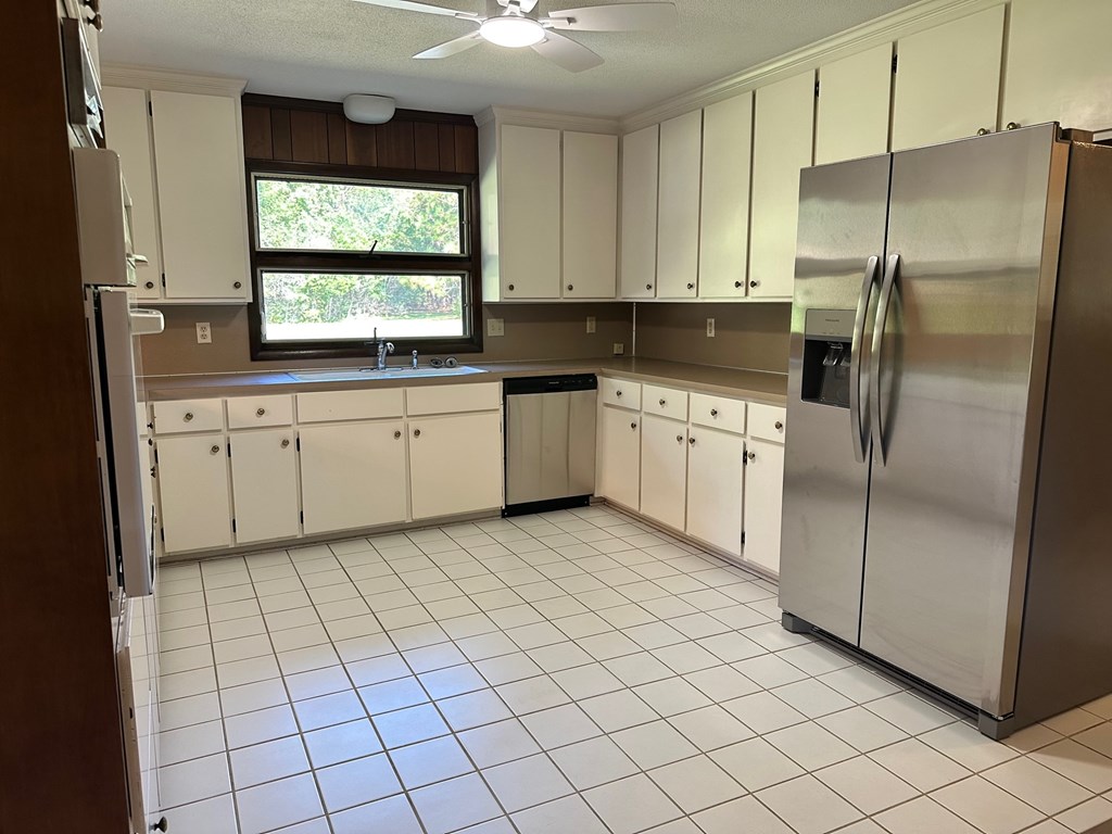 A kitchen with white cabinets and a stainless steel refrigerator.