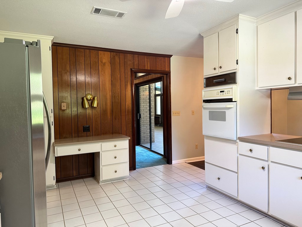 A kitchen with white cabinets and a wooden wall.