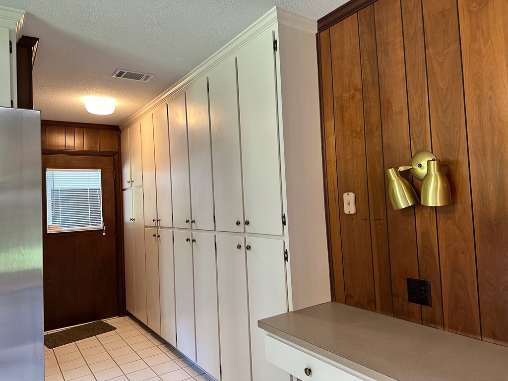 A kitchen with white cabinets and a wooden wall.