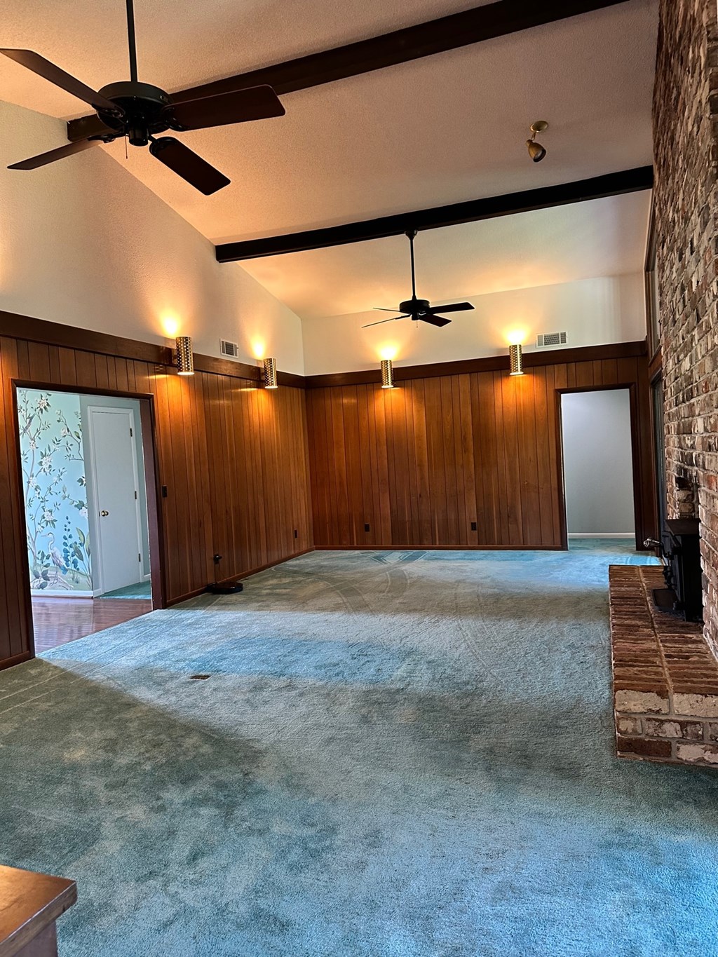 A room with a blue carpet and a ceiling fan.