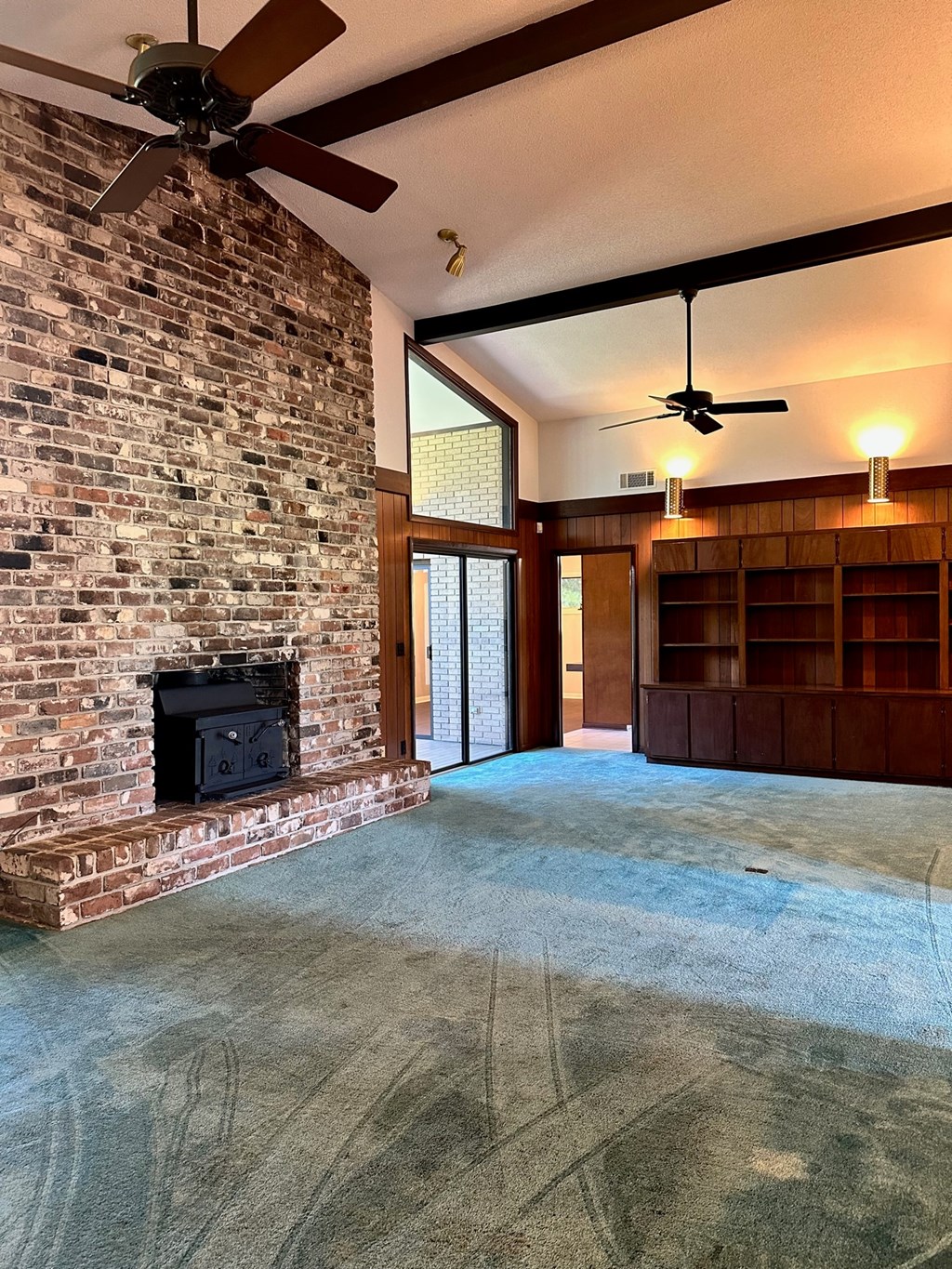 A room with a brick fireplace and a ceiling fan.