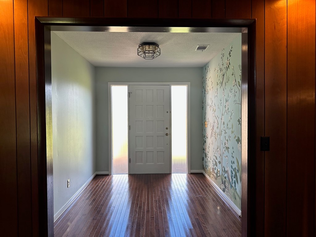 A hallway with a white door and wooden floors.