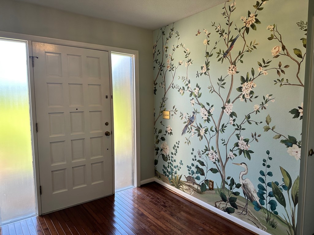 A room with a white door and a wallpapered wall with a floral design.