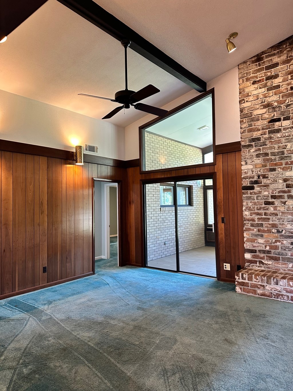 A room with a ceiling fan and a brick wall.