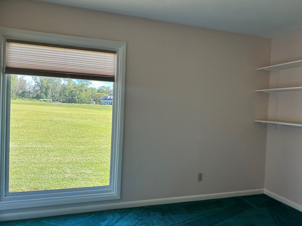 A room with a window overlooking a green field.