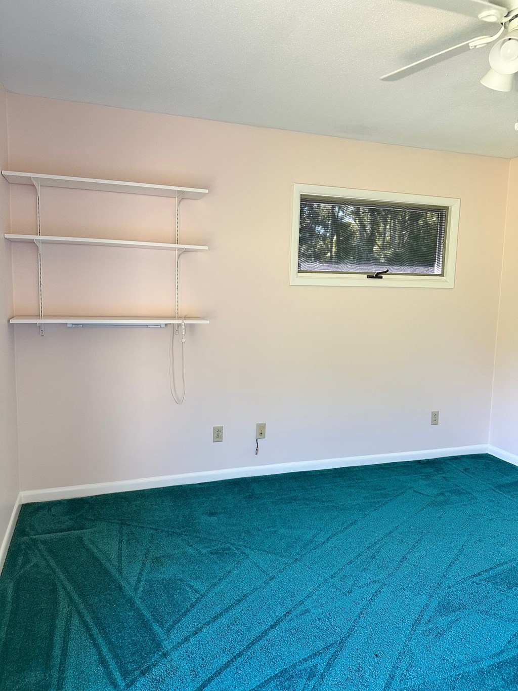 A room with a window and a ceiling fan.