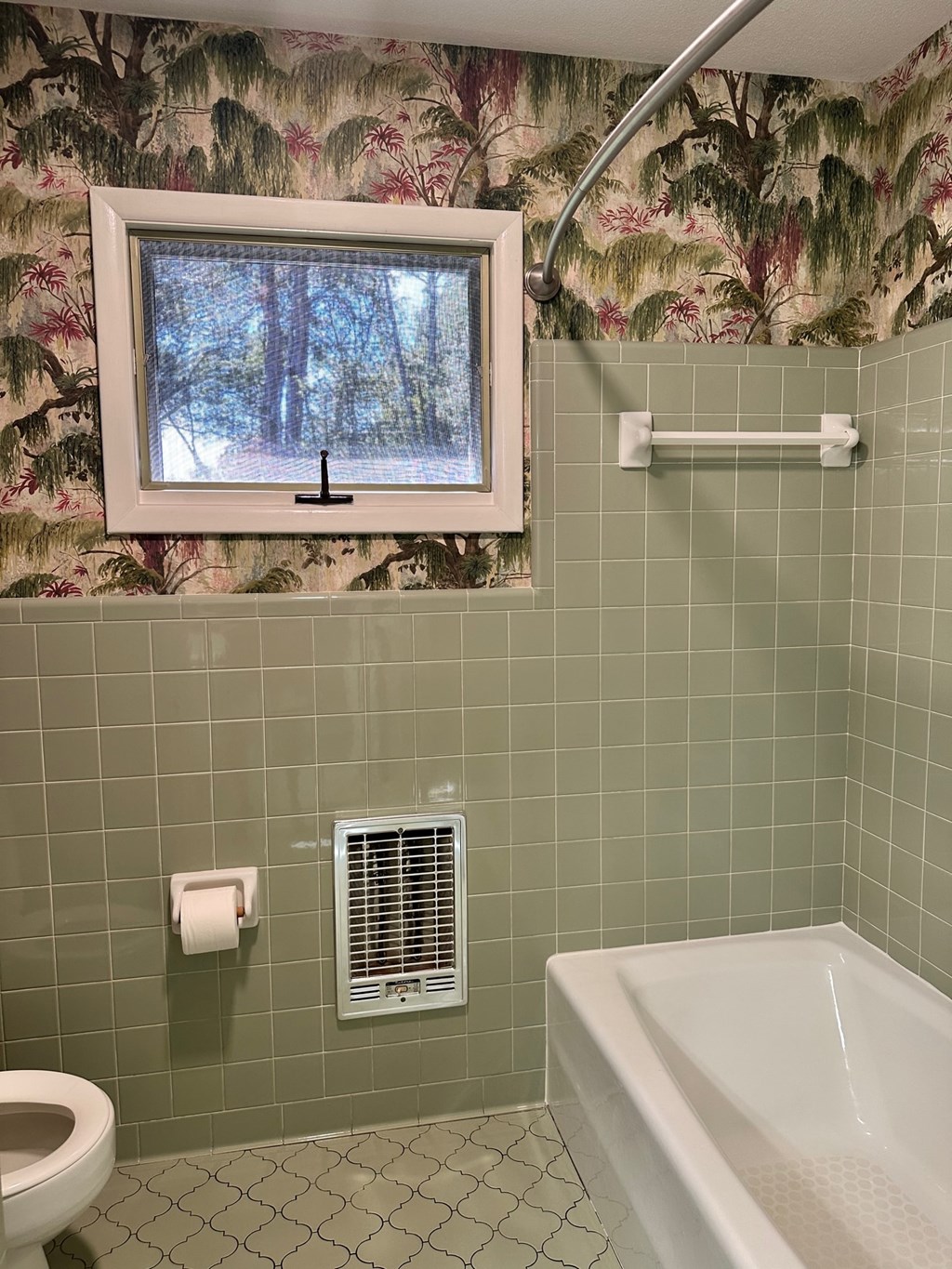 A bathroom with a green tiled wall and a window.