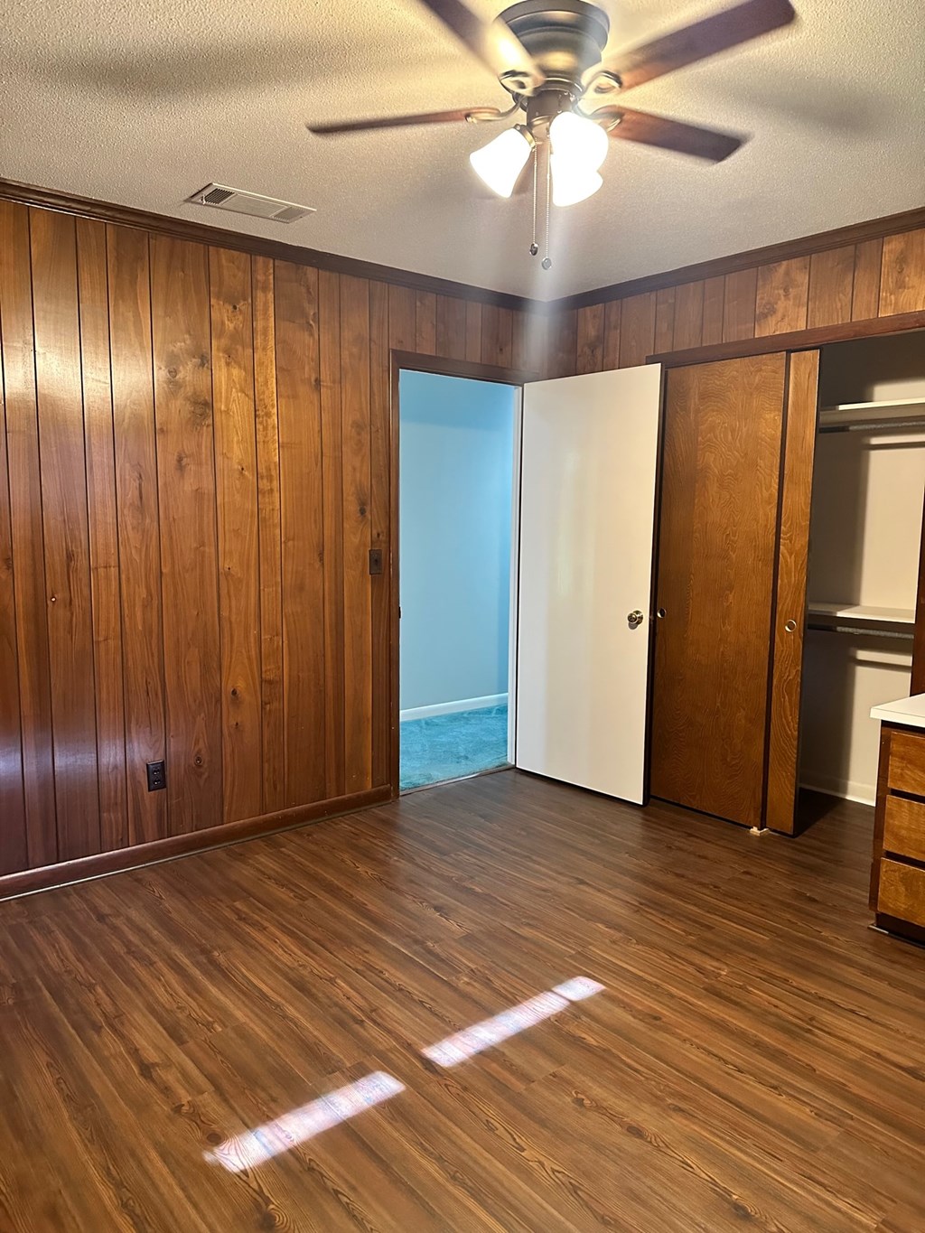 A room with wooden walls and floor and a ceiling fan.