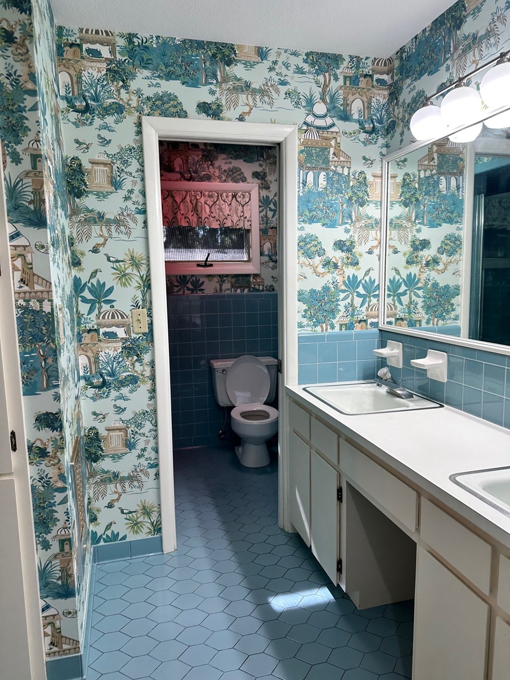 A bathroom with a toilet, sink, and a mirror.