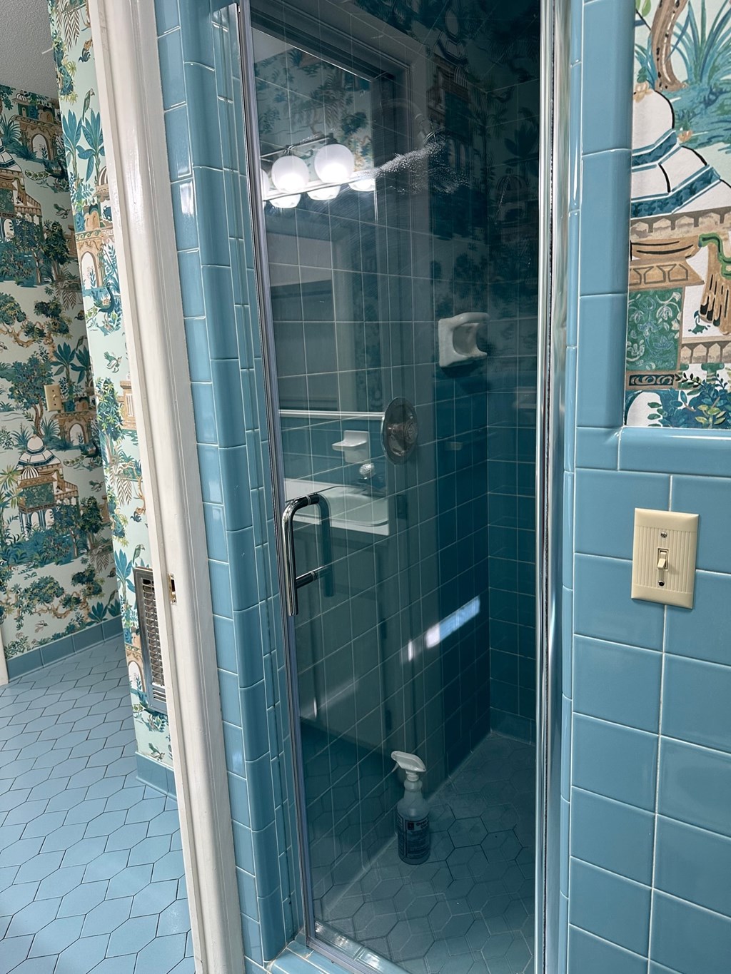 A shower stall with a glass door and a shower head.