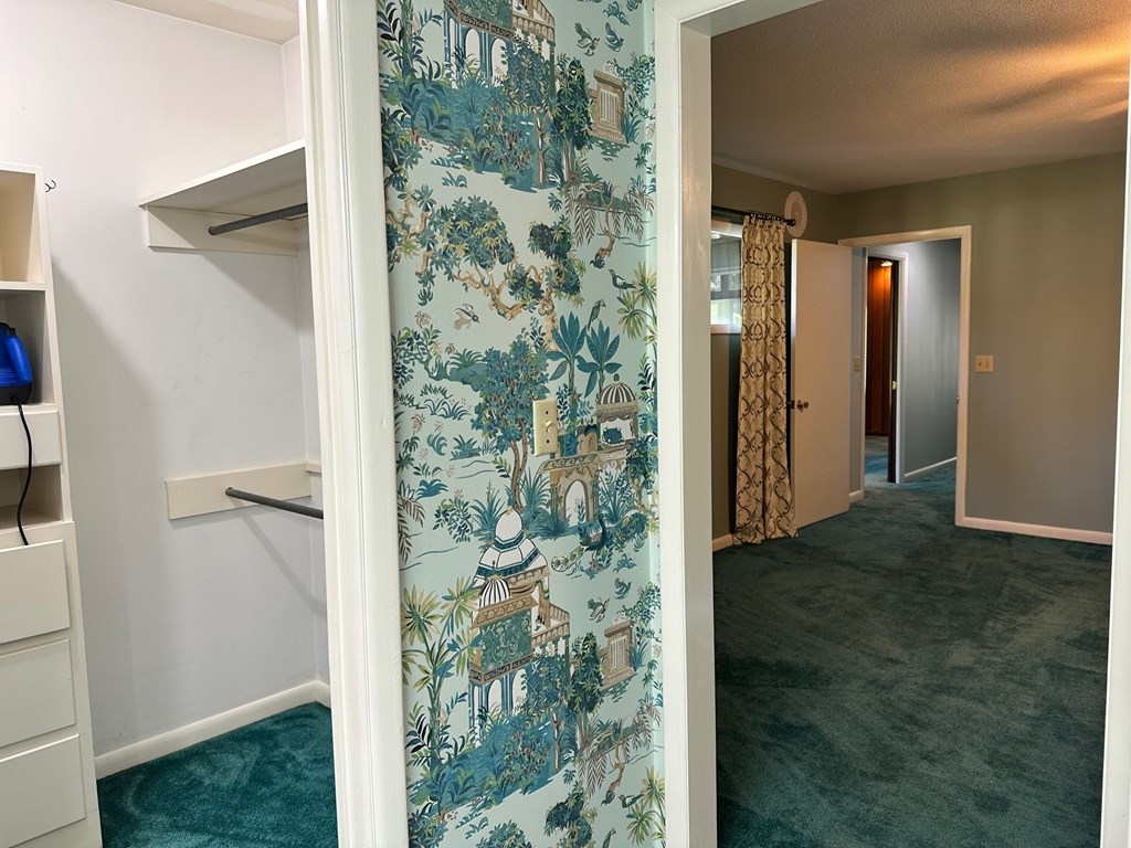 A room with a wallpapered wall and a carpeted floor.