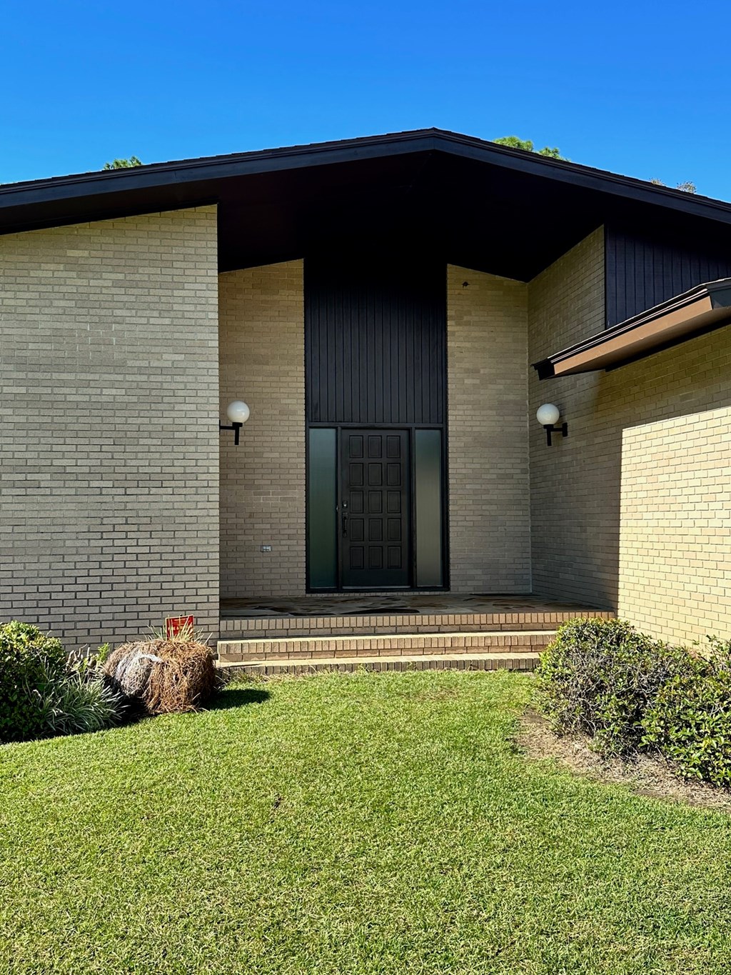 A house with a grey front and a green lawn.