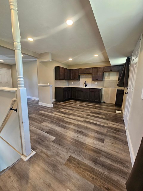 A kitchen with wooden floors and a white column.