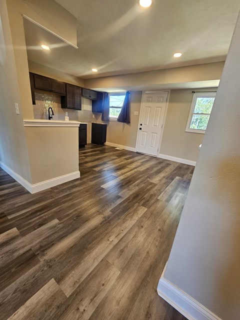 A kitchen with wood flooring and a white door.