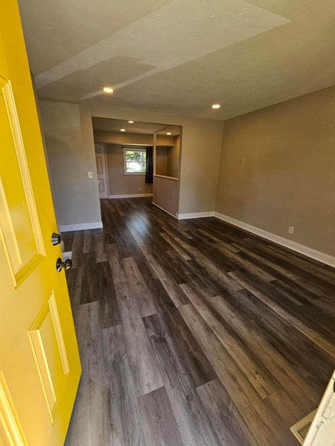 A room with a yellow door and wood flooring.