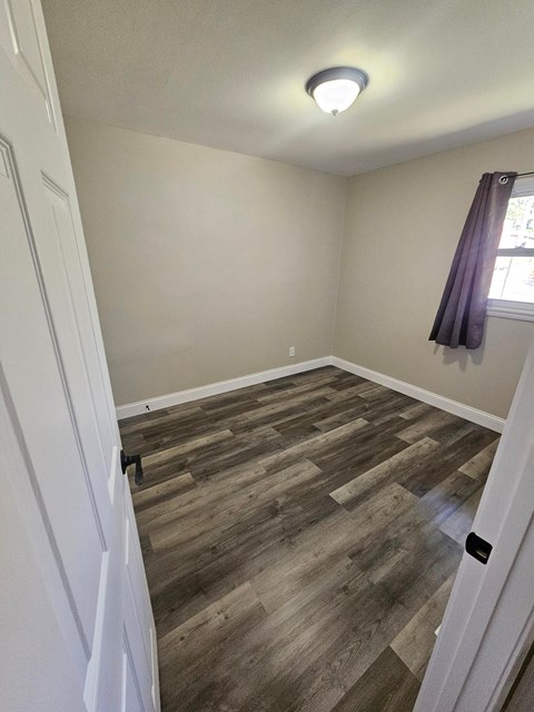 A room with wooden flooring and a white door.
