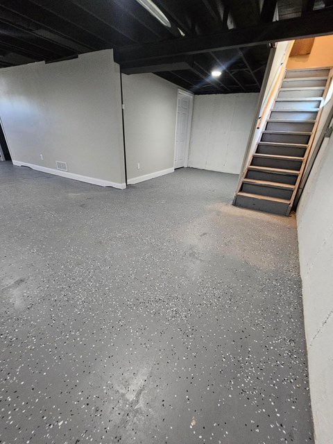 A room with a concrete floor and a staircase.