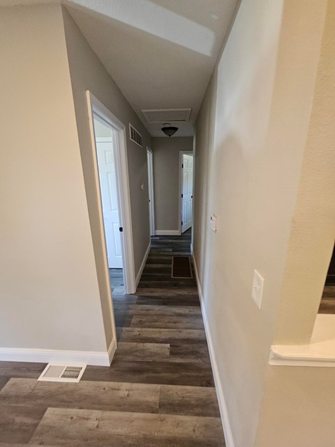 A hallway with a door on the left and a bench on the right.