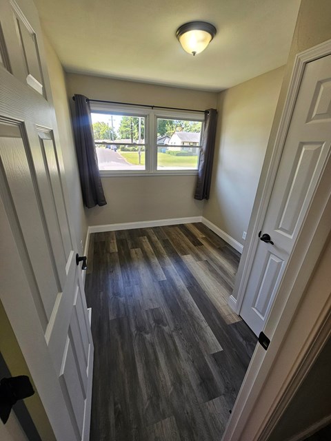 A hallway with a wooden floor and white walls.
