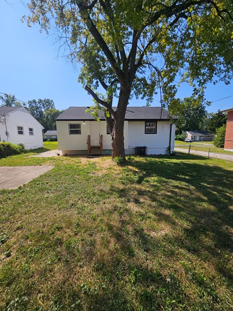 A white house with a tree in front of it.