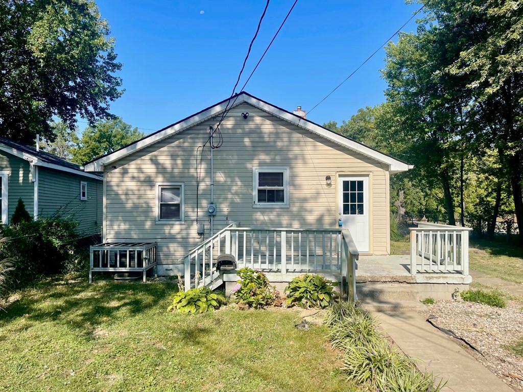 A house with a green lawn and trees in the background.