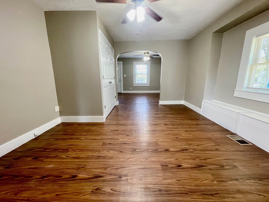 A long hallway with wood floors and a ceiling fan.