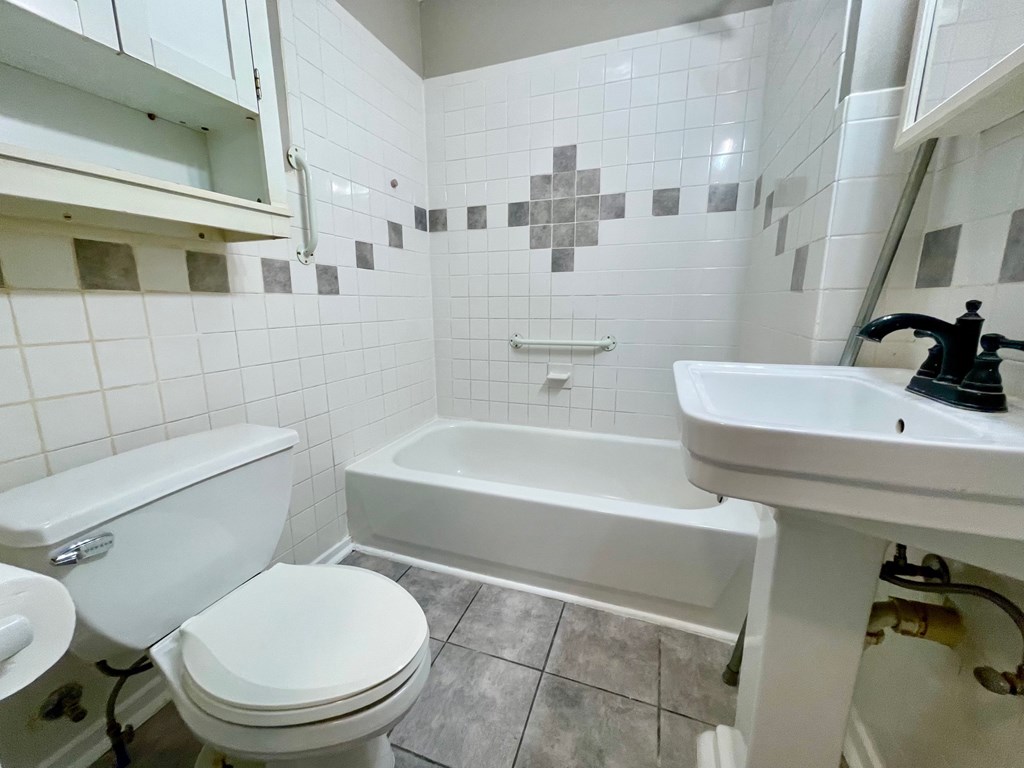 A white toilet sits next to a white sink in a bathroom.