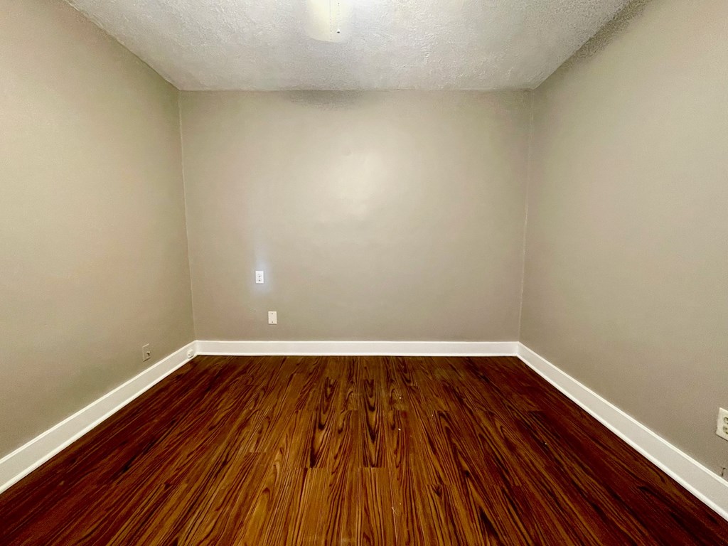 A room with wooden flooring and white walls.