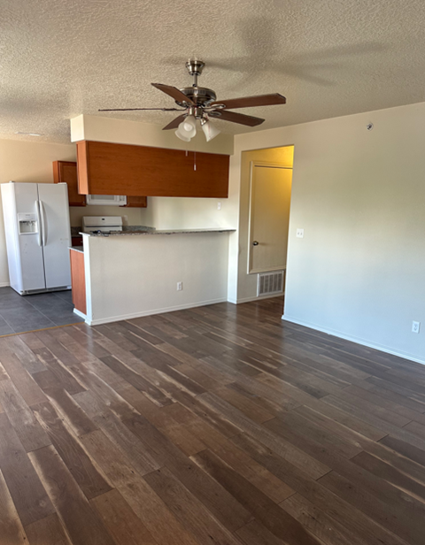 A room with a ceiling fan and wooden flooring.