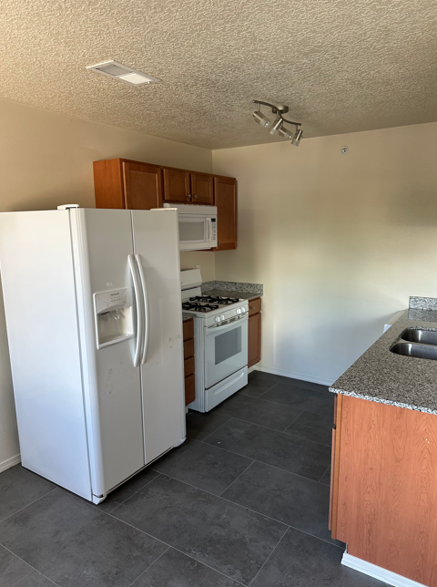 A white refrigerator is in a kitchen with a stove and microwave.