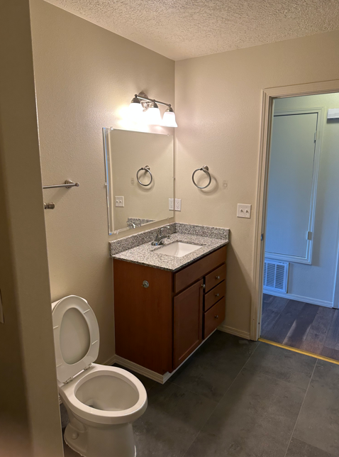 A bathroom with a toilet, sink, and mirror.